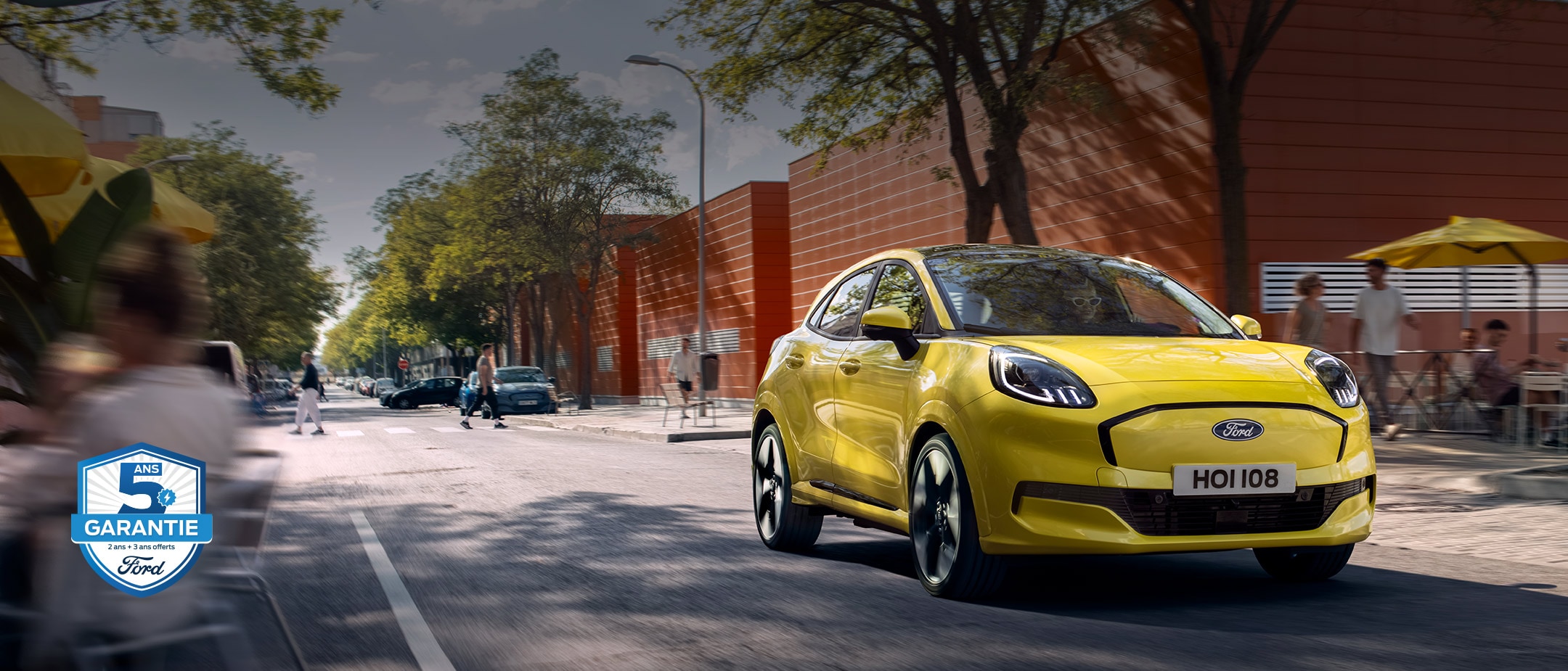 Vue avant d’une Ford Puma Gen-E® électrique jaune circulant en ville.