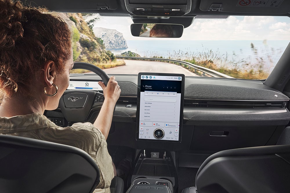 A person driving a Ford mustang mach-e whilst using sync 4 screen