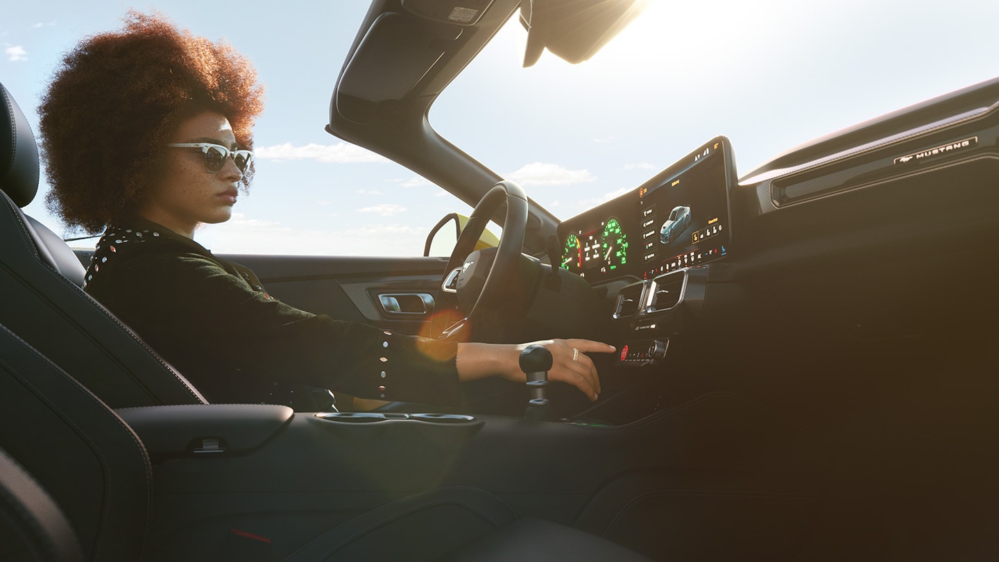 Habitacle de la Ford Mustang cabriolet avec conductrice en train de changer les paramètres 