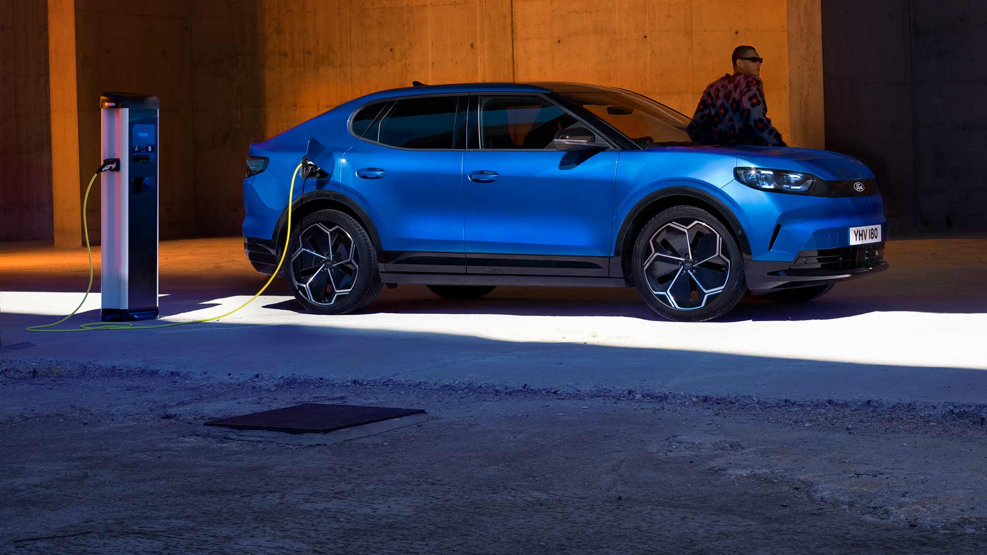 Ford Capri® électrique bleue branchée à une borne de recharge publique.