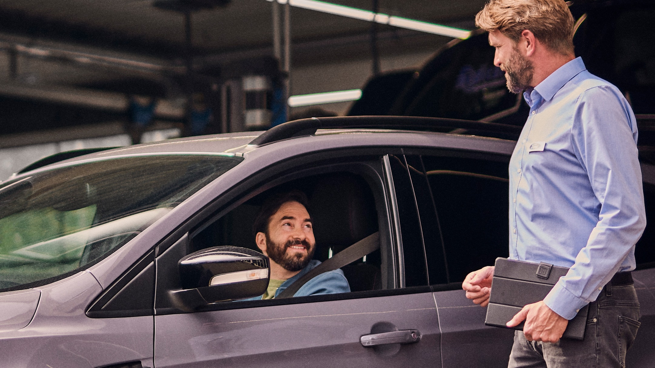 Un client Ford Service souriant dans une Ford grise